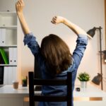 Frau stretcht sich vor ihrem Arbeitsplatz