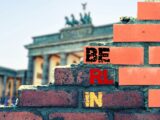 Klassenfahrt Berlin: Backsteinmauer mit Schriftzug „Berlin“ und Blick auf das Brandenburger Tor
