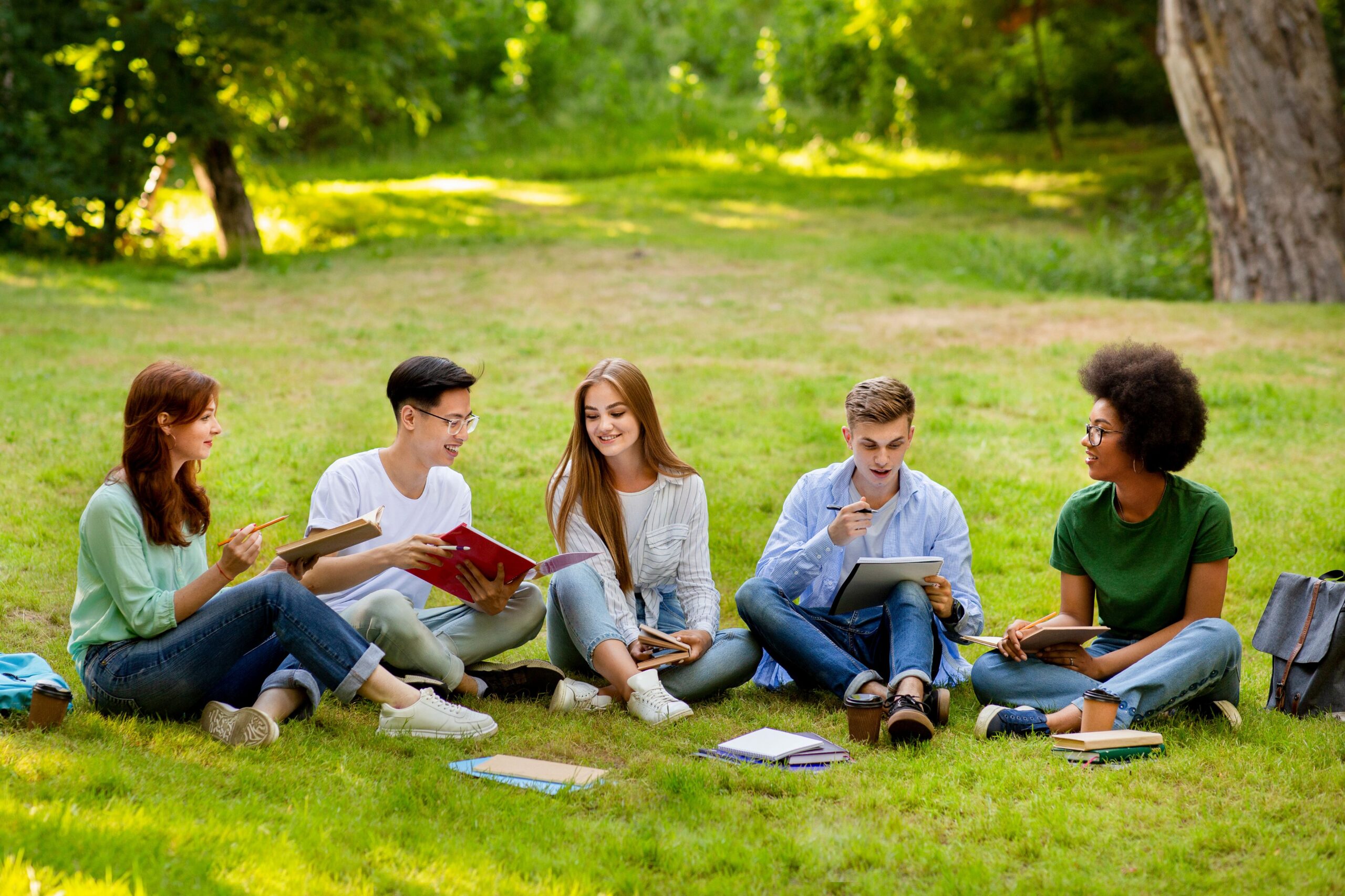 Schülergruppe sitzt auf Wiese und lernt gemeinsam, symbolisch für nachhaltige Erfahrungen bei einer Klassenfahrt Berlin