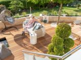 Holzterrasse mit Lounge-Sofa und Hängesessel im Garten | Sonnensegel für Terrasse